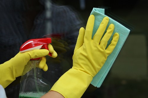 Cleaner wearing protective gloves and checking a floor area for hazards